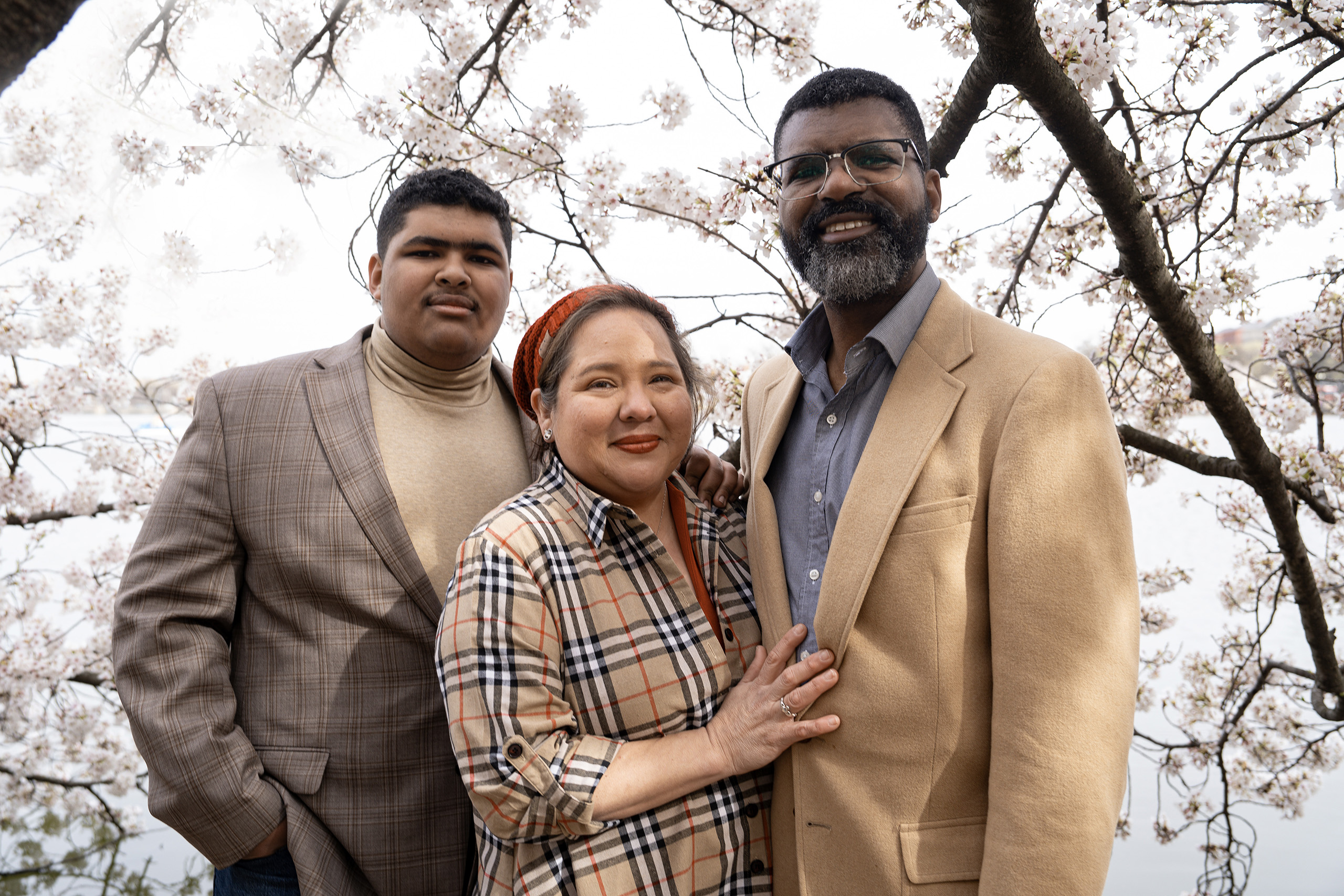 A family portrait of the Fosters in front of some cherry blossoms.